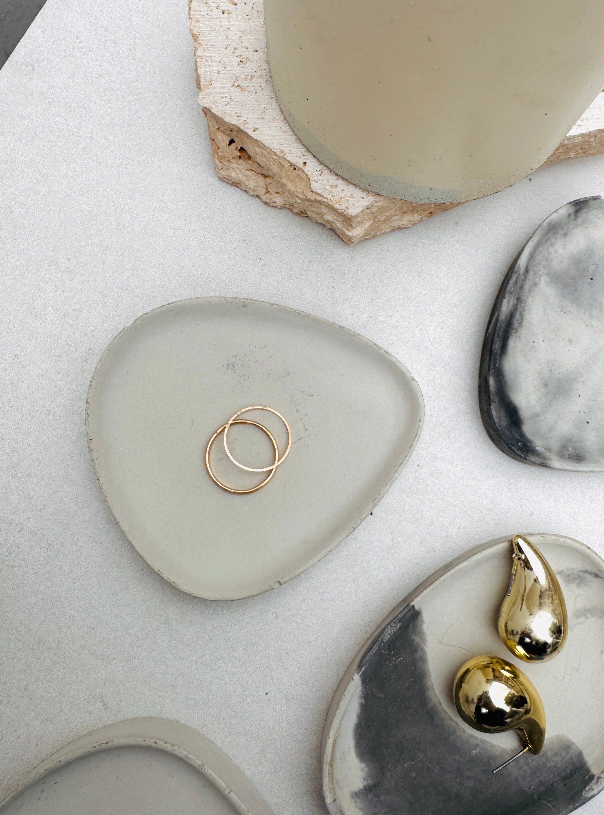 Jewelry displayed on natural stone surfaces with a ceramic mug in the background.